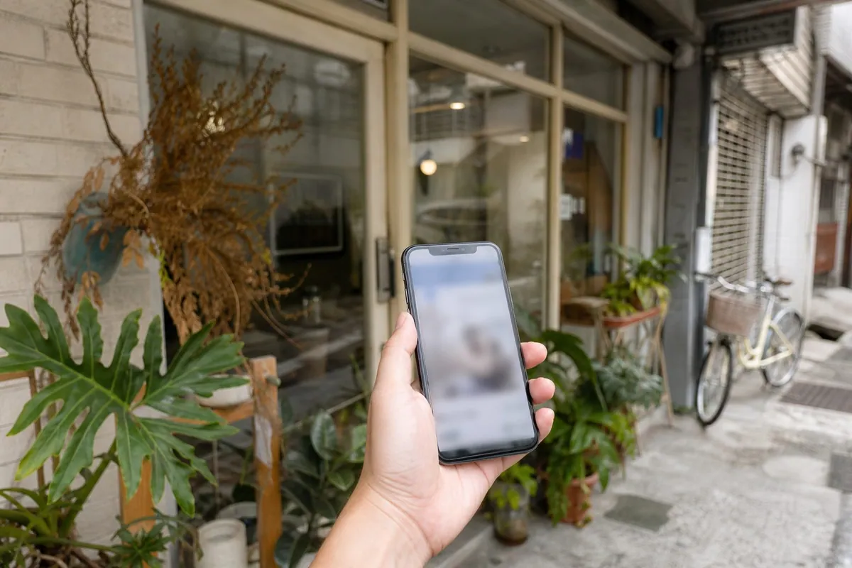 小店門口，一隻手拿著 iPhone